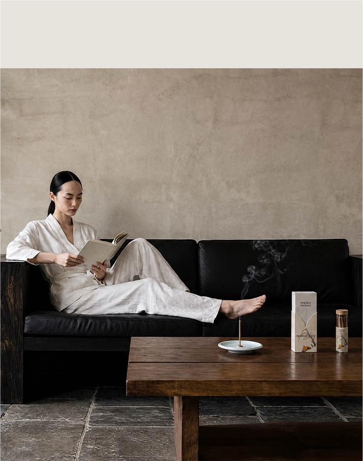 Woman reading on a sofa beside incense